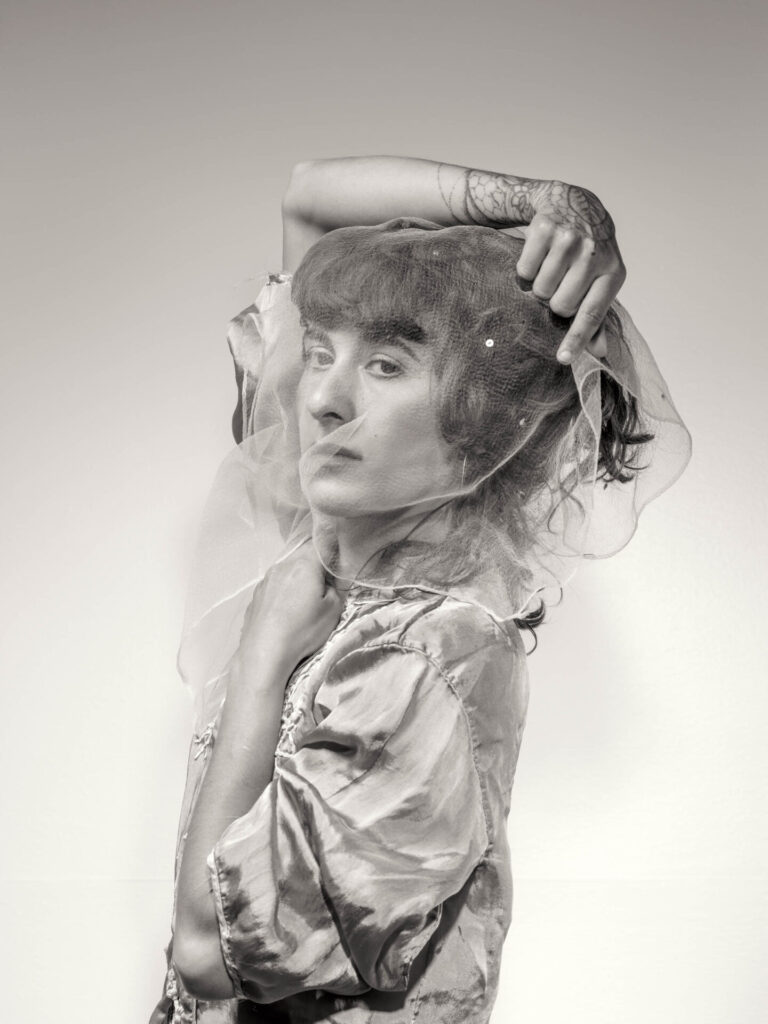 black and white photograph of a female figure behind a veil